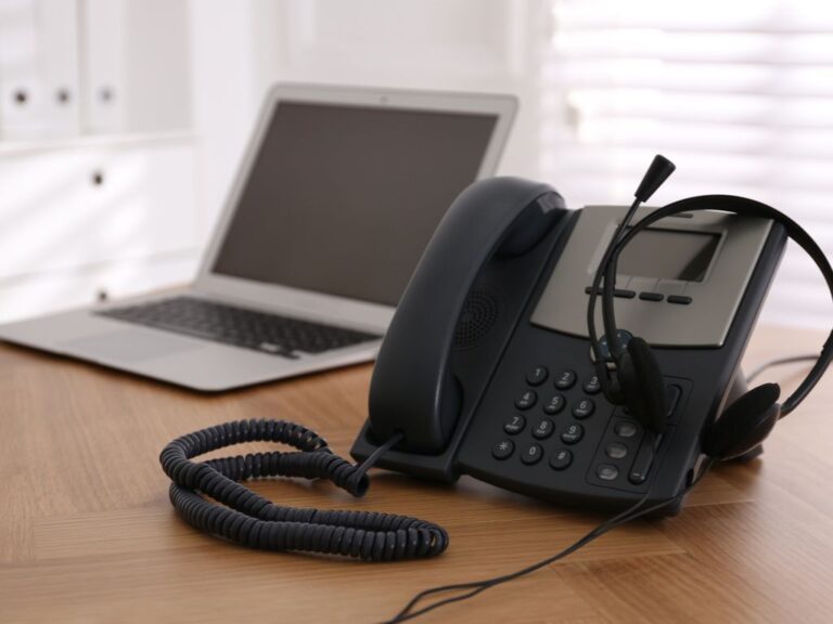 mesa con telefono audifonos y pc